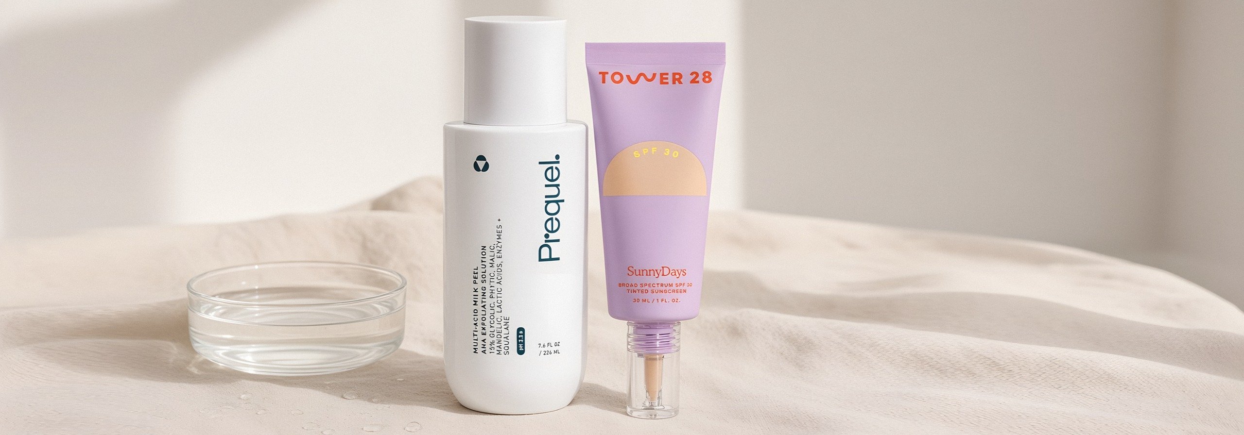 Prequel Multi-Acid Milk Peel and Tower 28 SunnyDays SPF 30 on cream linen beside a glass dish of water